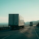Two semi-trucks driving on a highway.