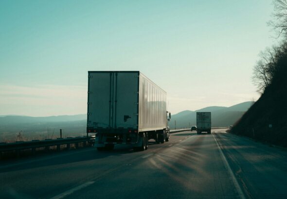 Two semi-trucks driving on a highway.
