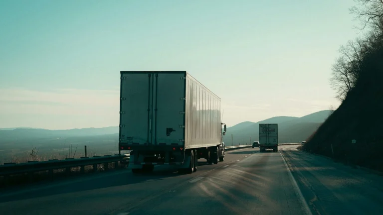 Two semi-trucks driving on a highway.