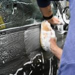 a man washing a car with a sponge