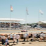 A race car speeds along the track surrounded by crowds.