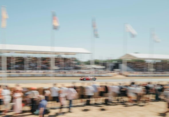 A race car speeds along the track surrounded by crowds.