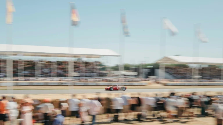A race car speeds along the track surrounded by crowds.