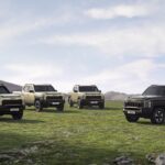 A group of four trucks parked in a field