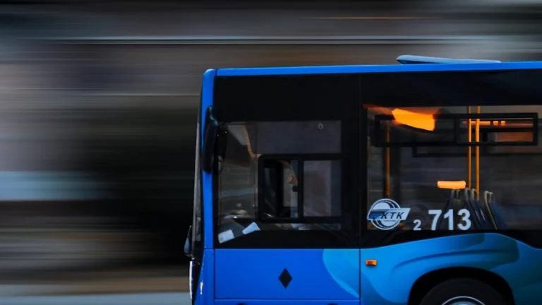 a blue bus driving down a street next to a tall building