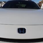 White car with blue honda logo on hood