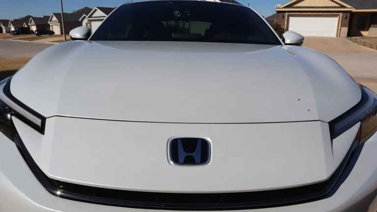 White car with blue honda logo on hood