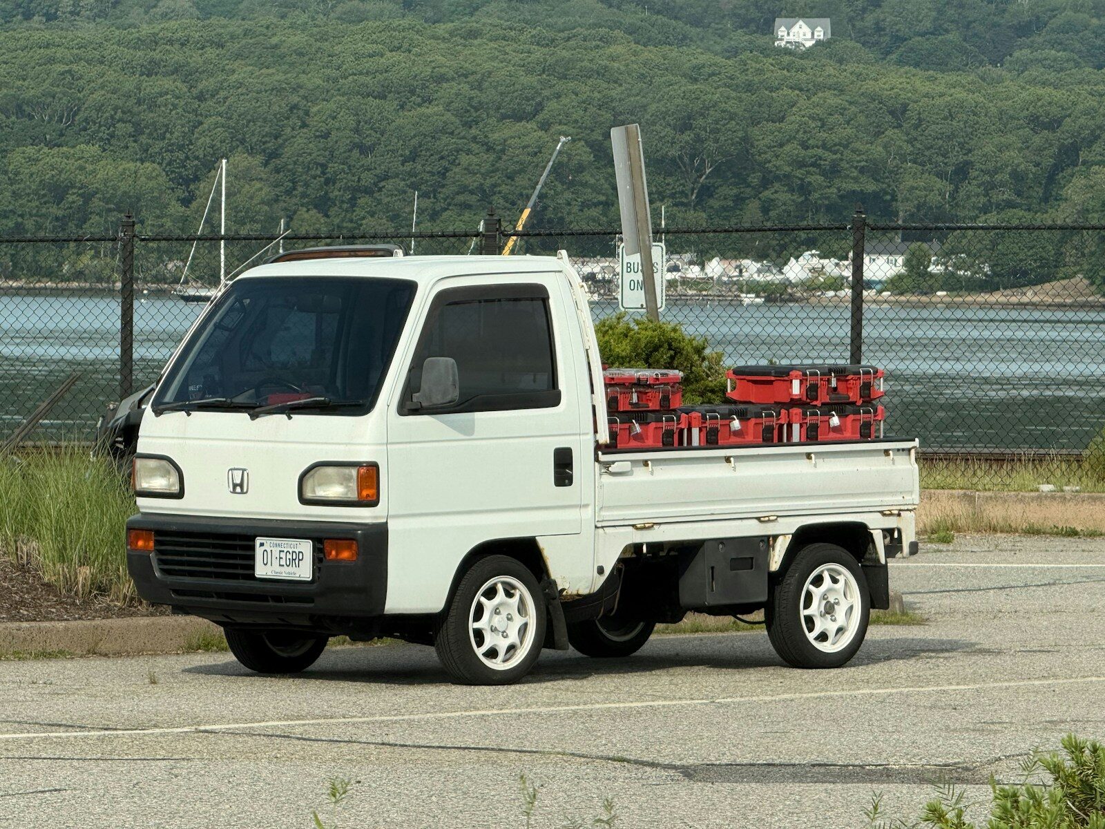 A white utility truck with red crates parked near water.