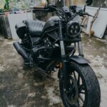 A black cruiser motorcycle parked outdoors on a concrete surface.