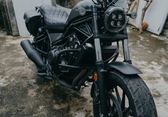 A black cruiser motorcycle parked outdoors on a concrete surface.
