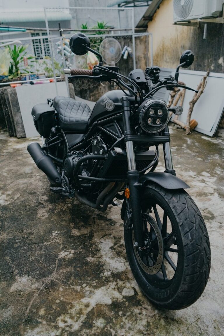 A black cruiser motorcycle parked outdoors on a concrete surface.