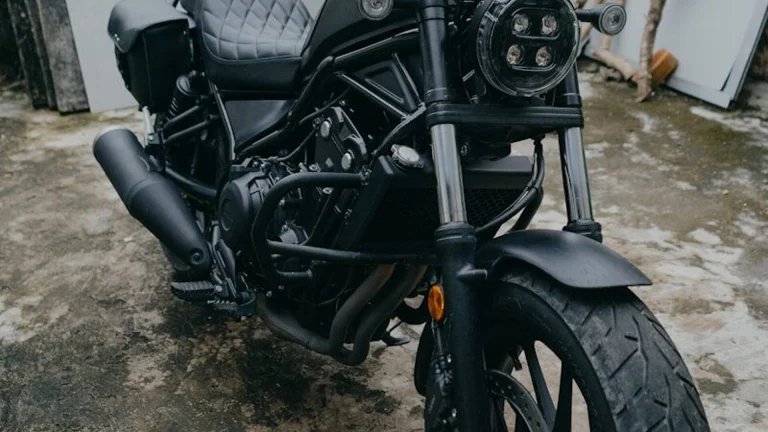 A black cruiser motorcycle parked outdoors on a concrete surface.