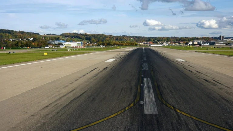 An empty airport runway with buildings in the distance