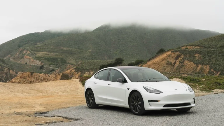 white sedan parked beside mountain during daytime