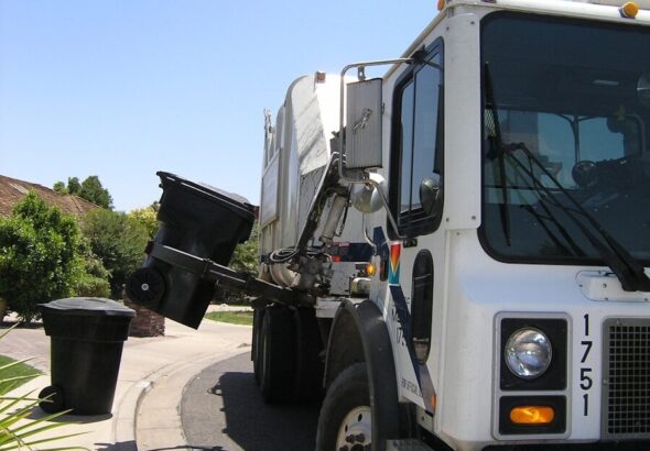 Residential garbage truck collecting trash cans on a suburban street