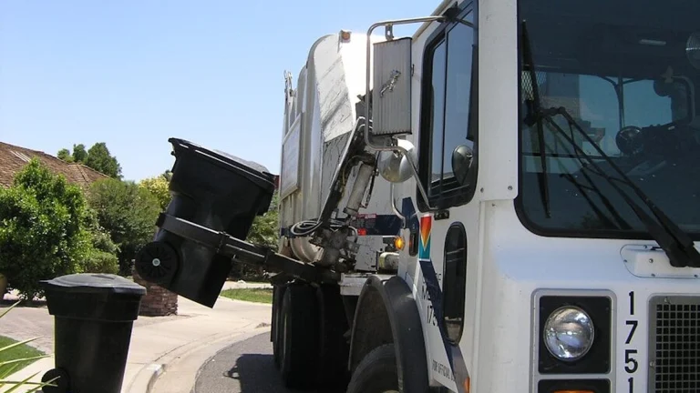 Residential garbage truck collecting trash cans on a suburban street