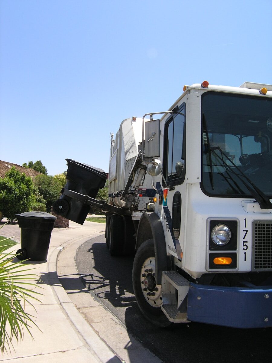 Residential garbage truck collecting trash cans on a suburban street