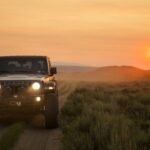 black jeep wrangler on green grass field during sunset