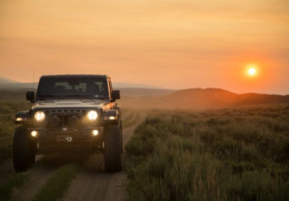 black jeep wrangler on green grass field during sunset