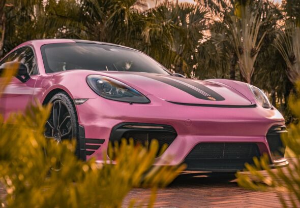 a pink sports car parked in front of some trees
