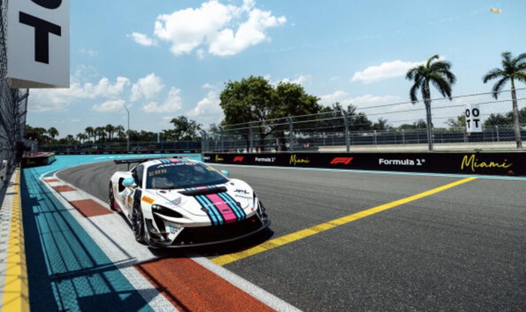 A McLaren Artura Trophy race car on track at the Miami International Autodrome, with Formula 1 Miami Grand Prix branding visible on the barriers.