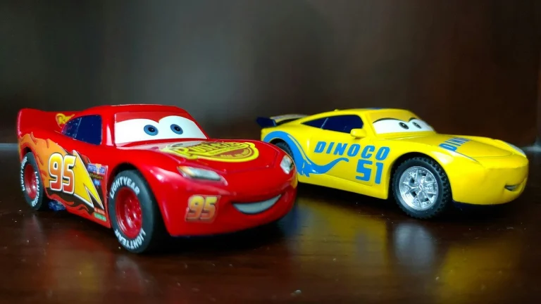two red and yellow Disney Cars plastic toys on brown wooden surface