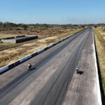 Two motorcycles racing on a long asphalt track