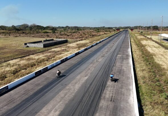 Two motorcycles racing on a long asphalt track