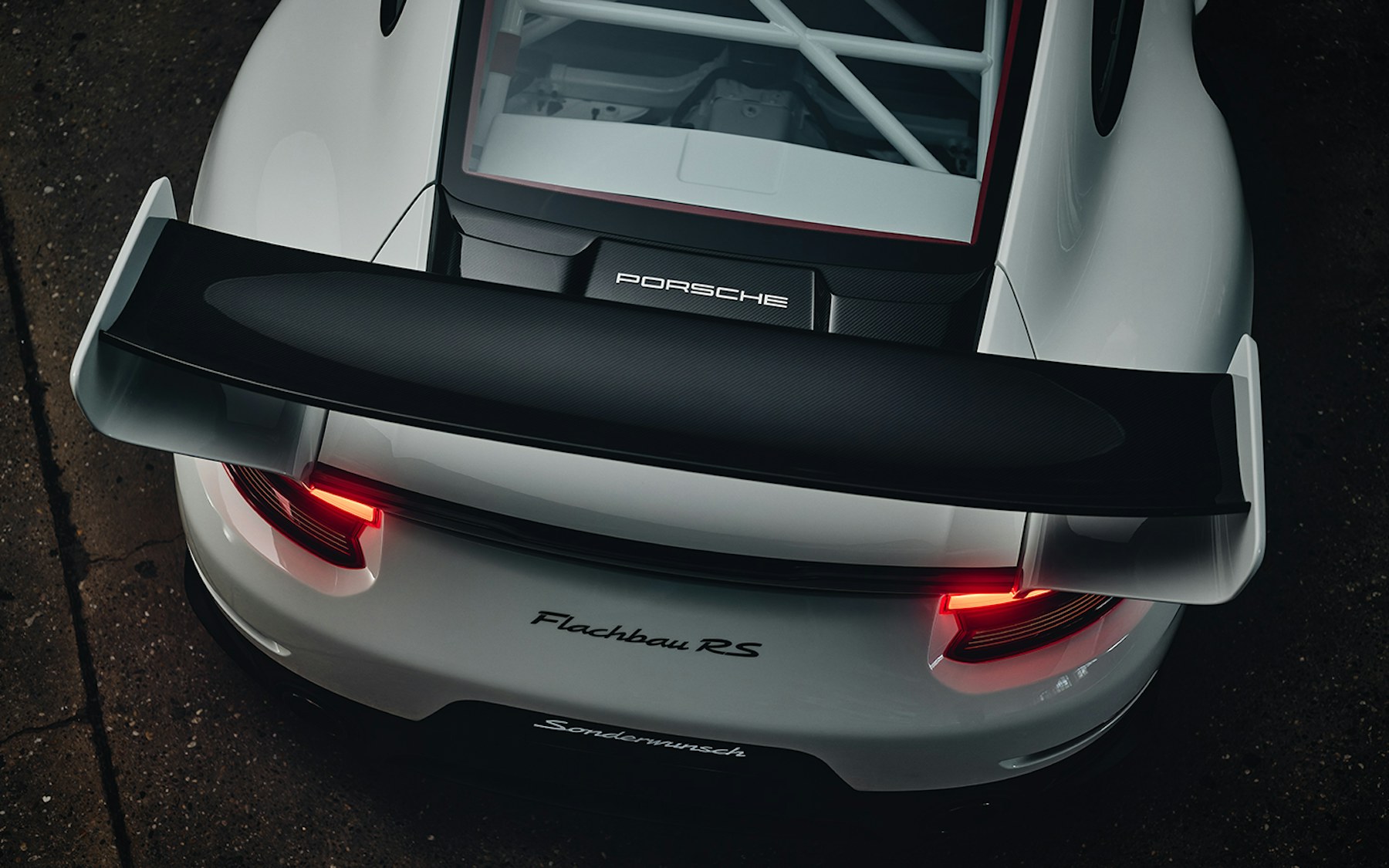 Rear view of the Porsche 911 Flachbau RS showing the adjustable rear wing with S-shaped mounts and Grand Prix White aero discs