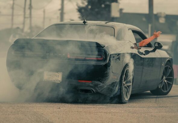 Black car doing a burnout with smoke billowing out