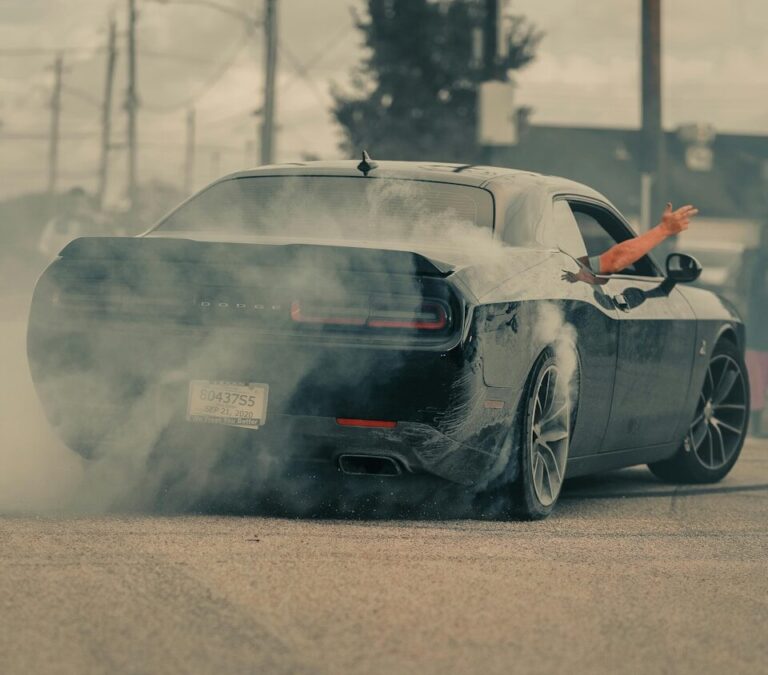 Black car doing a burnout with smoke billowing out
