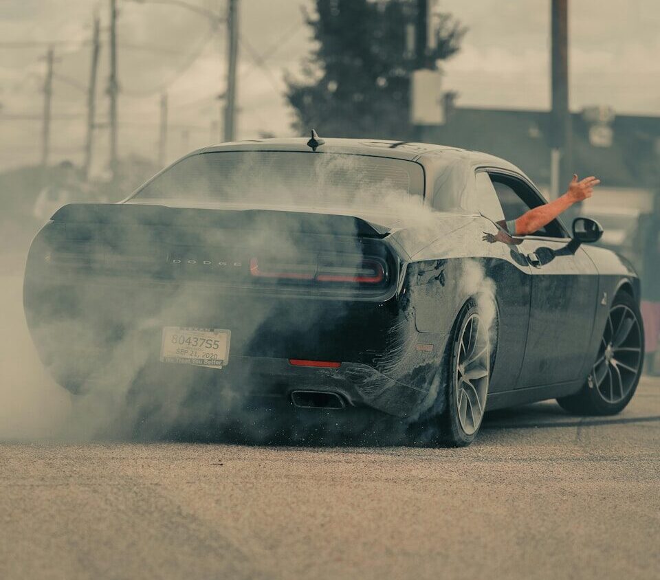 Black car doing a burnout with smoke billowing out