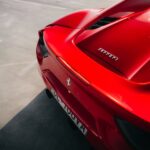 The rear of a red Ferrari sports car parked on grey concrete