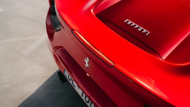 The rear of a red Ferrari sports car parked on grey concrete