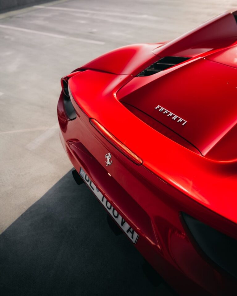 The rear of a red Ferrari sports car parked on grey concrete
