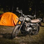 brown naked motorcycle parked beside orange camping tent