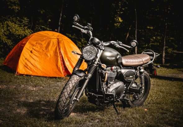 brown naked motorcycle parked beside orange camping tent