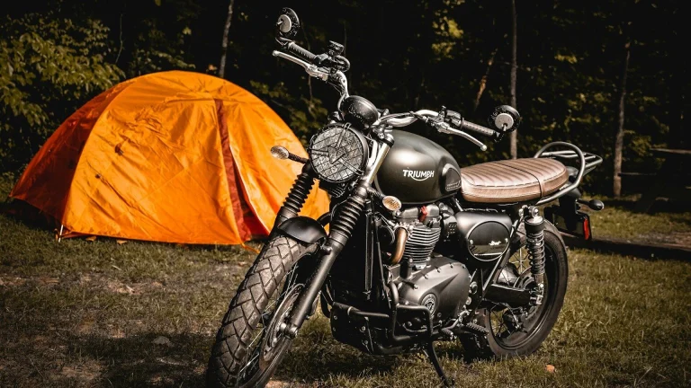 brown naked motorcycle parked beside orange camping tent