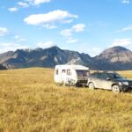 black suv on brown grass field near mountain under blue sky during daytime