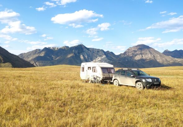 black suv on brown grass field near mountain under blue sky during daytime
