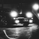 Black sports car with headlights on at night