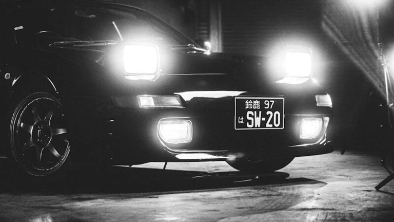 Black sports car with headlights on at night