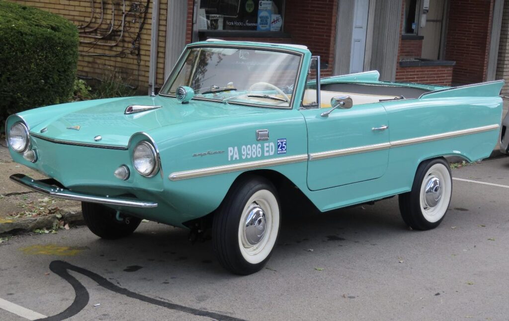 A restored mint-green 1966 Amphicar 770 convertible parked on a street, shown on its road wheels