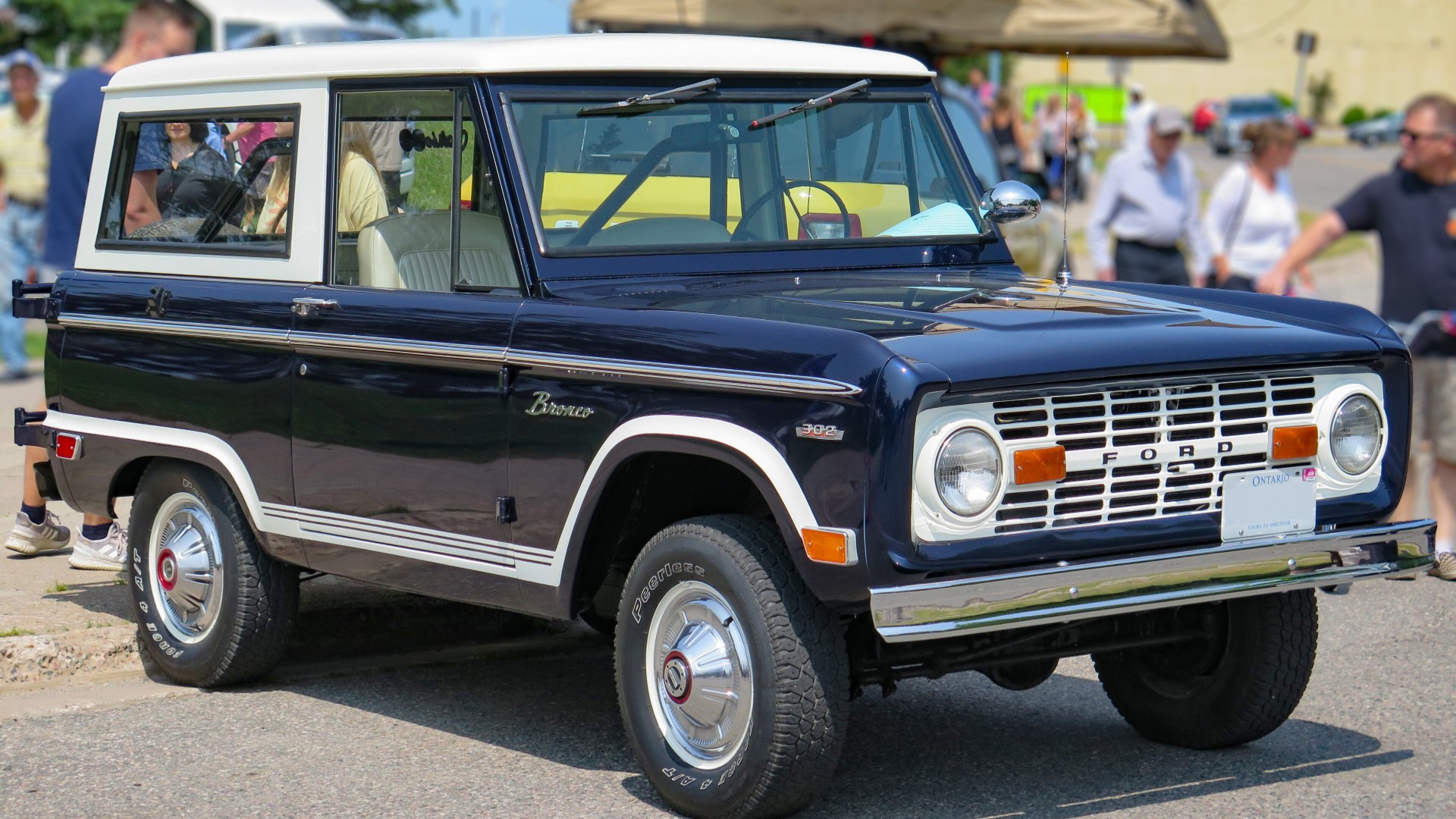 A navy blue and white 1969 Ford Bronco wagon parked on a street