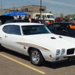 White 1970 Pontiac GTO Judge with Judge stripes and Ram Air hood parked at a car show