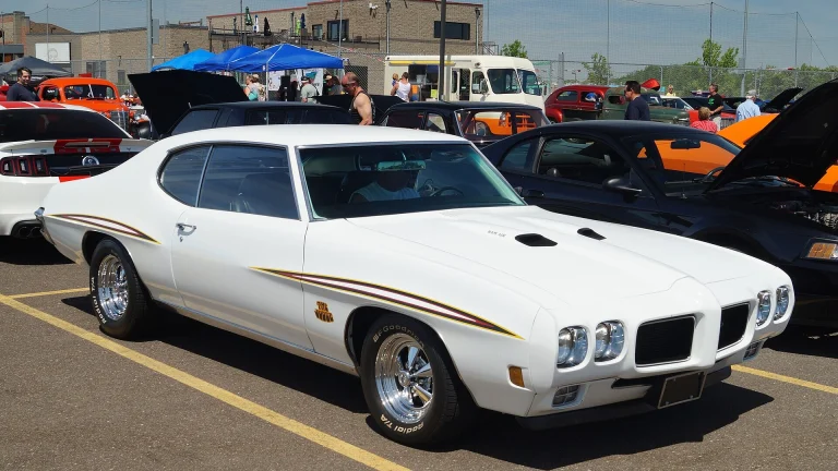 White 1970 Pontiac GTO Judge with Judge stripes and Ram Air hood parked at a car show