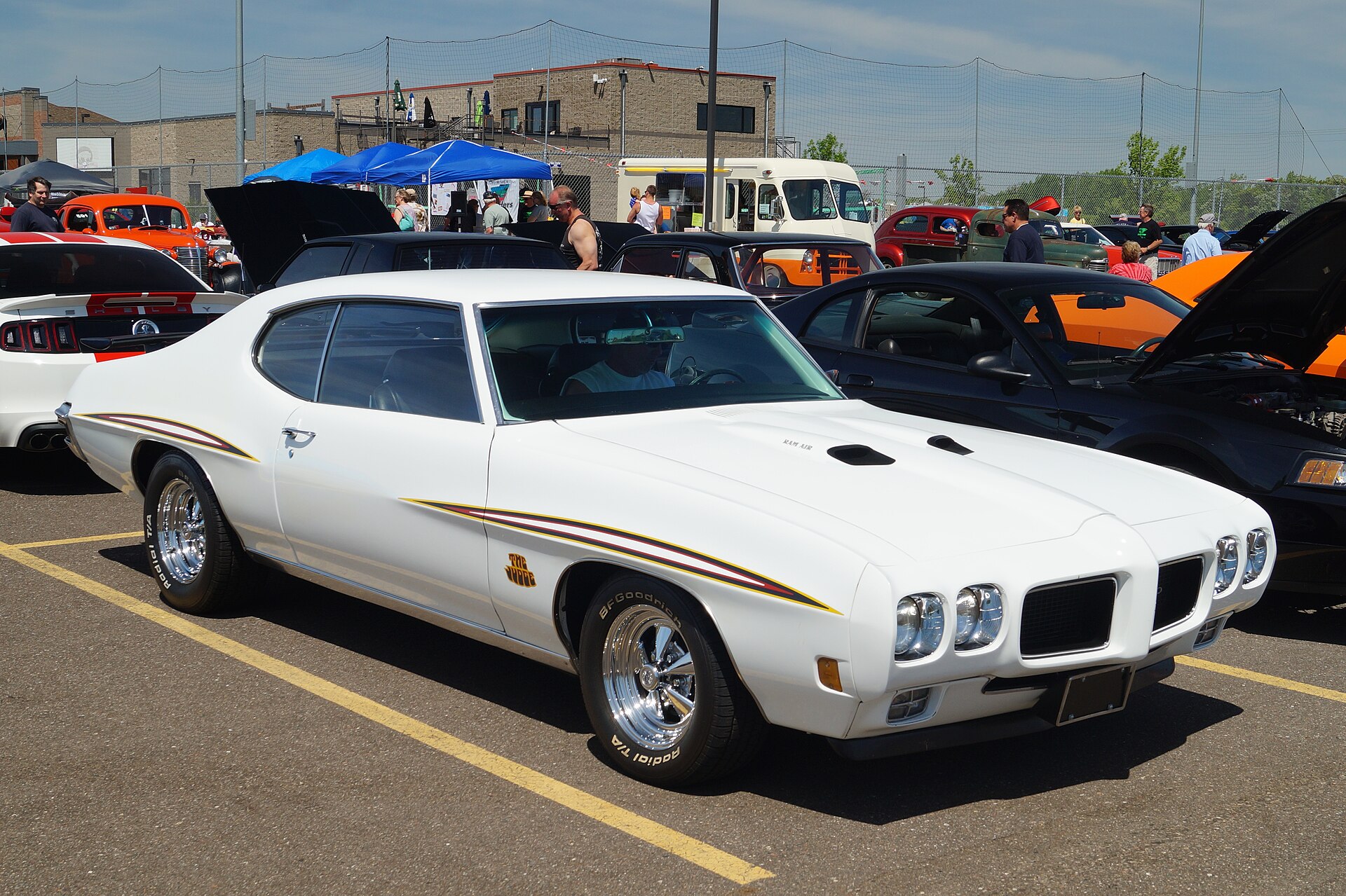 White 1970 Pontiac GTO Judge with Judge stripes and Ram Air hood parked at a car show