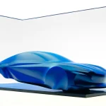 Blue draped sculpture previewing the third-generation Alpine A110 on a floating black plinth