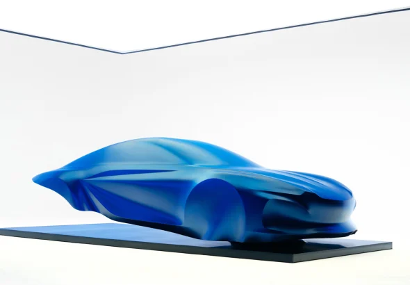 Blue draped sculpture previewing the third-generation Alpine A110 on a floating black plinth