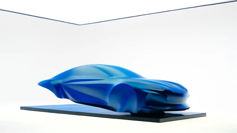Blue draped sculpture previewing the third-generation Alpine A110 on a floating black plinth